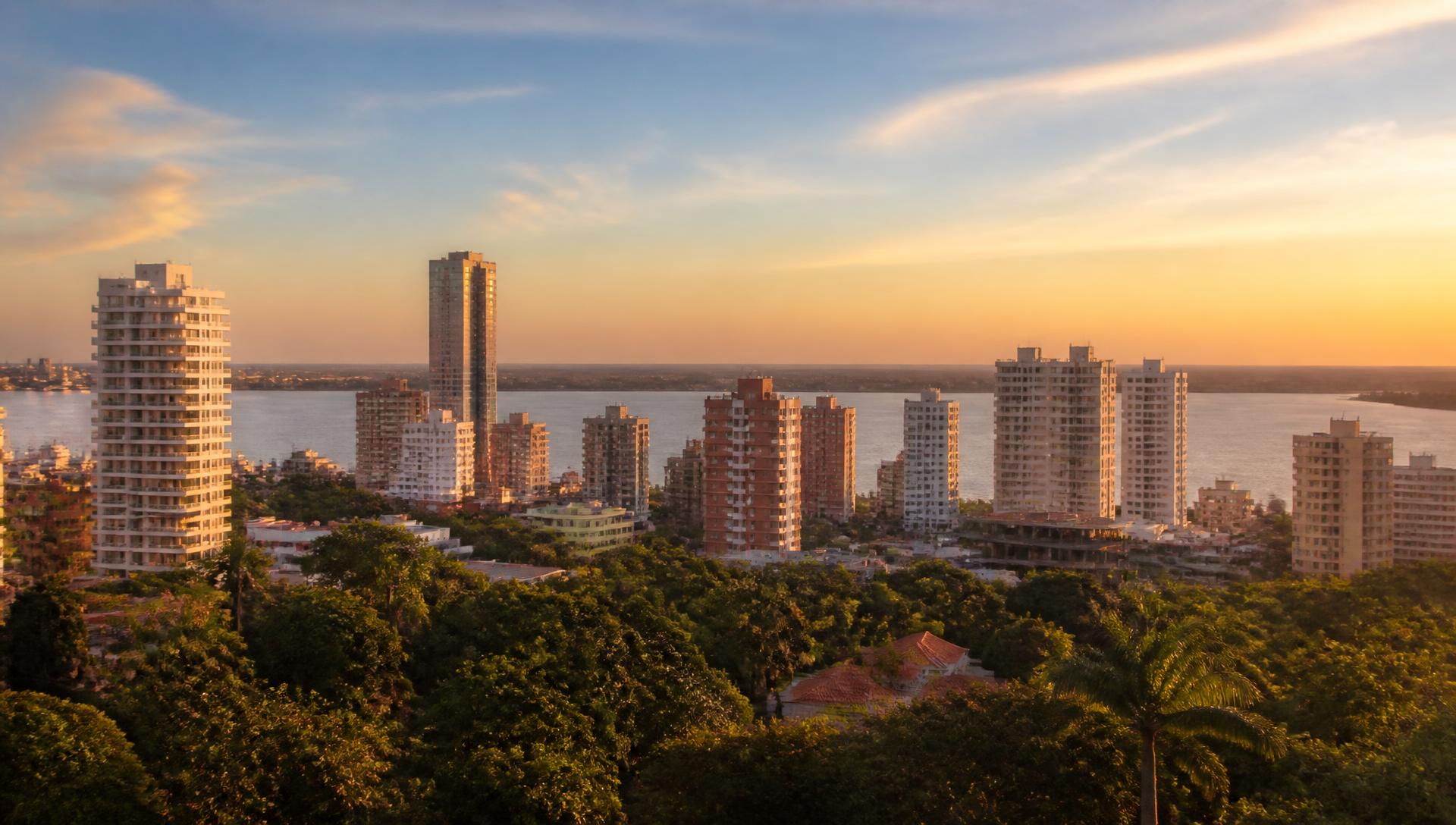 Skyline van Asunción bij zonsondergang met appartementengebouwen boven groene bomen